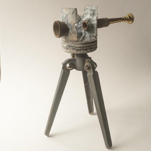 Assemblage sculpture that resembles a broken looking glass, eroded in the middle. It is made from reclaimed instrument, car, and camera parts.